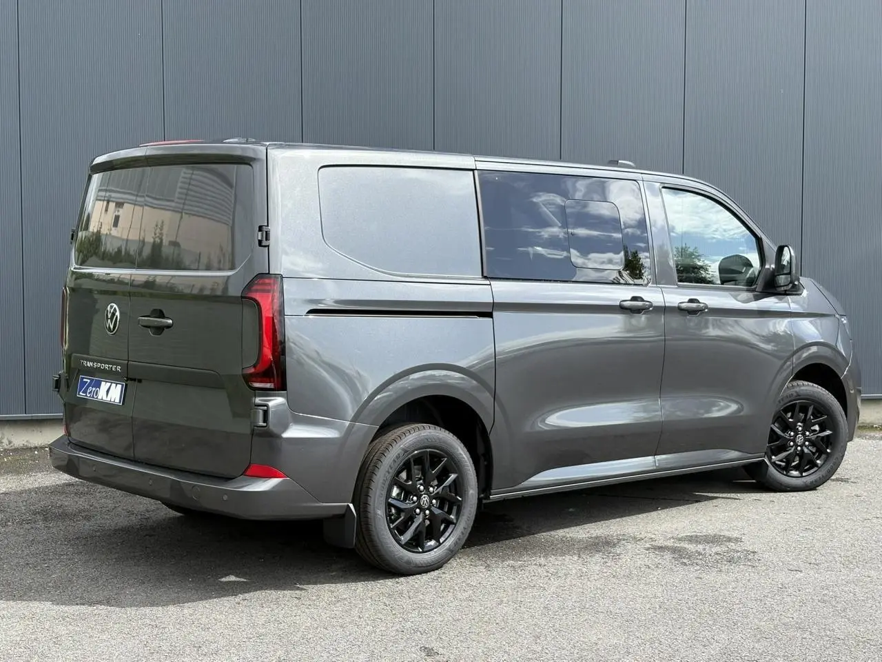 Vue 3/4 arrière droite du Volkswagen Transporter T7 ProCab graphite métallisé avec jantes noires et feux arrière LED.