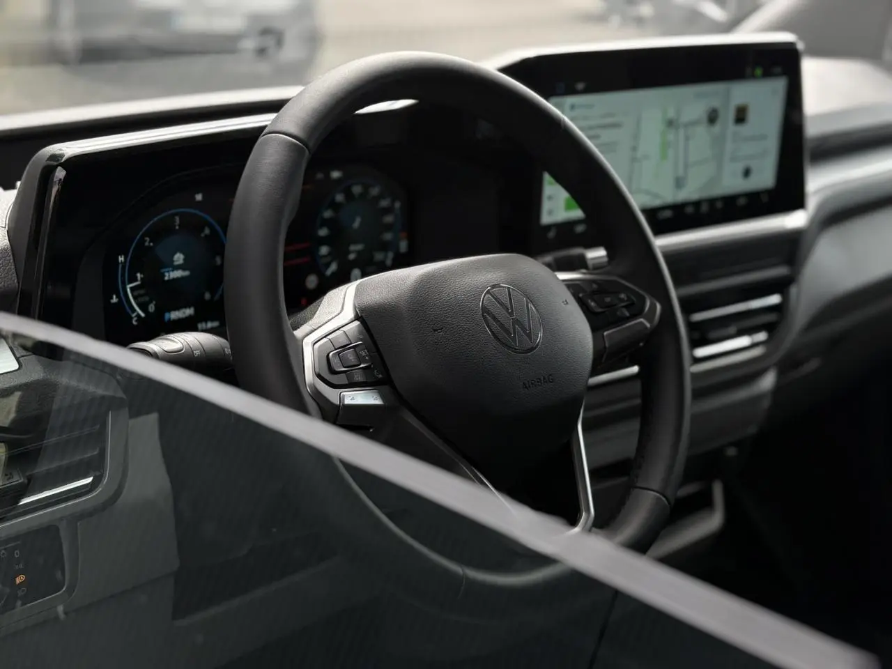 Vue intérieure du volant multifonction noir du Volkswagen Transporter T7 avec tableau de bord numérique et écran tactile.