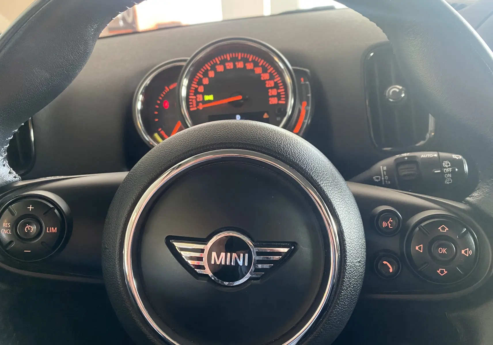 Vue rapprochée du volant en cuir noir avec logo MINI et tableau de bord éclairé en rouge du MINI Countryman 2018.