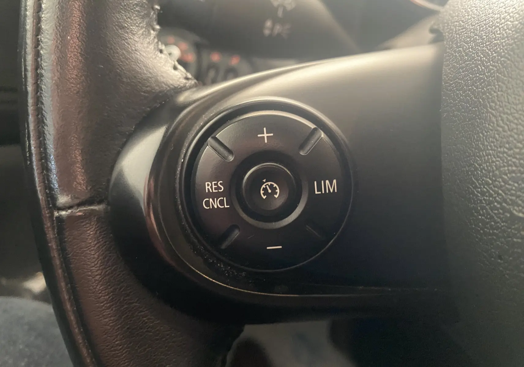 Gros plan sur les commandes de régulateur de vitesse au volant cuir noir d'une MINI Countryman rouge toit noir.