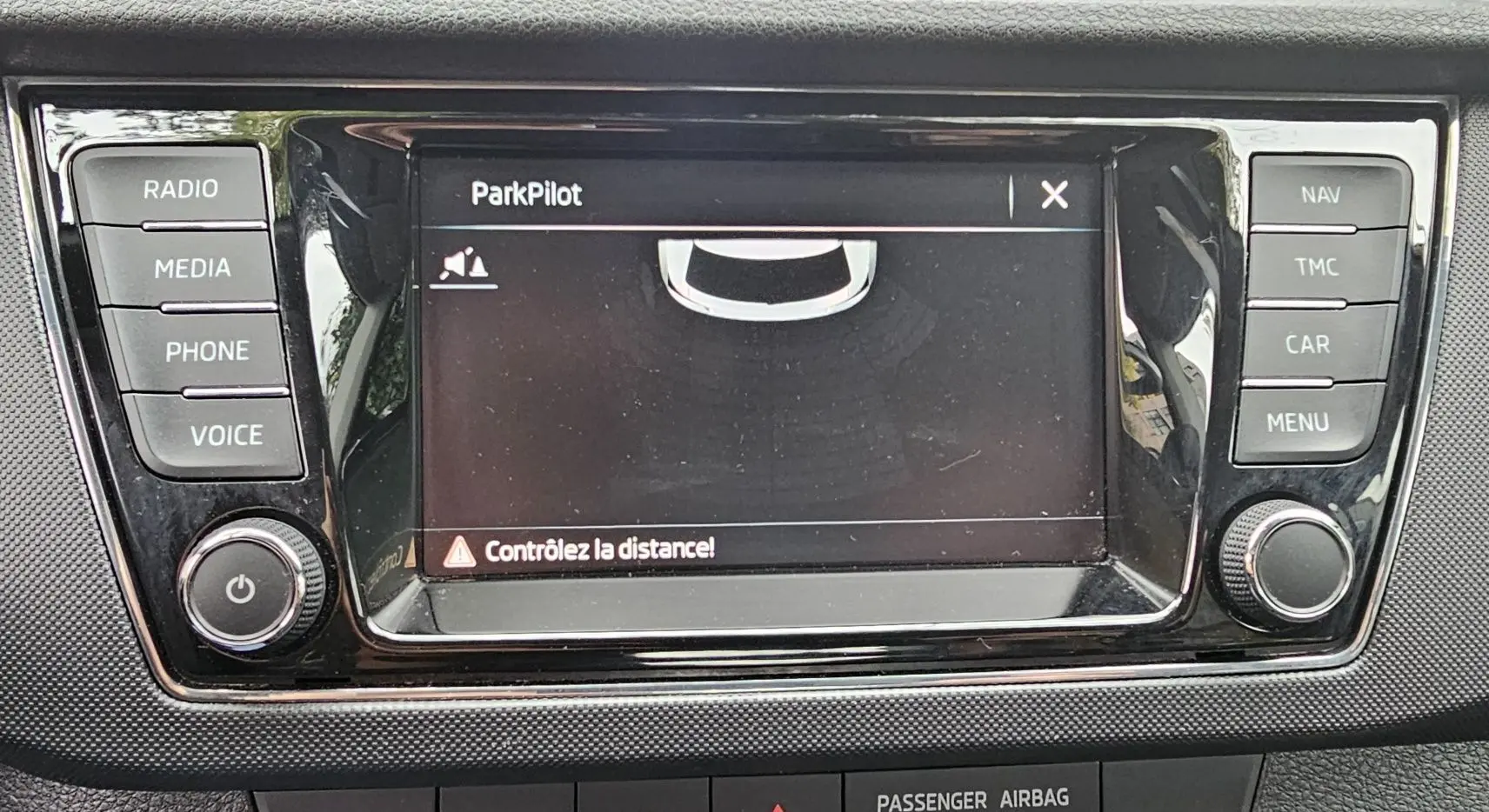 Écran central tactile du système de navigation Amundsen sur Skoda Fabia blanche, affichant l'aide au stationnement ParkPilot.