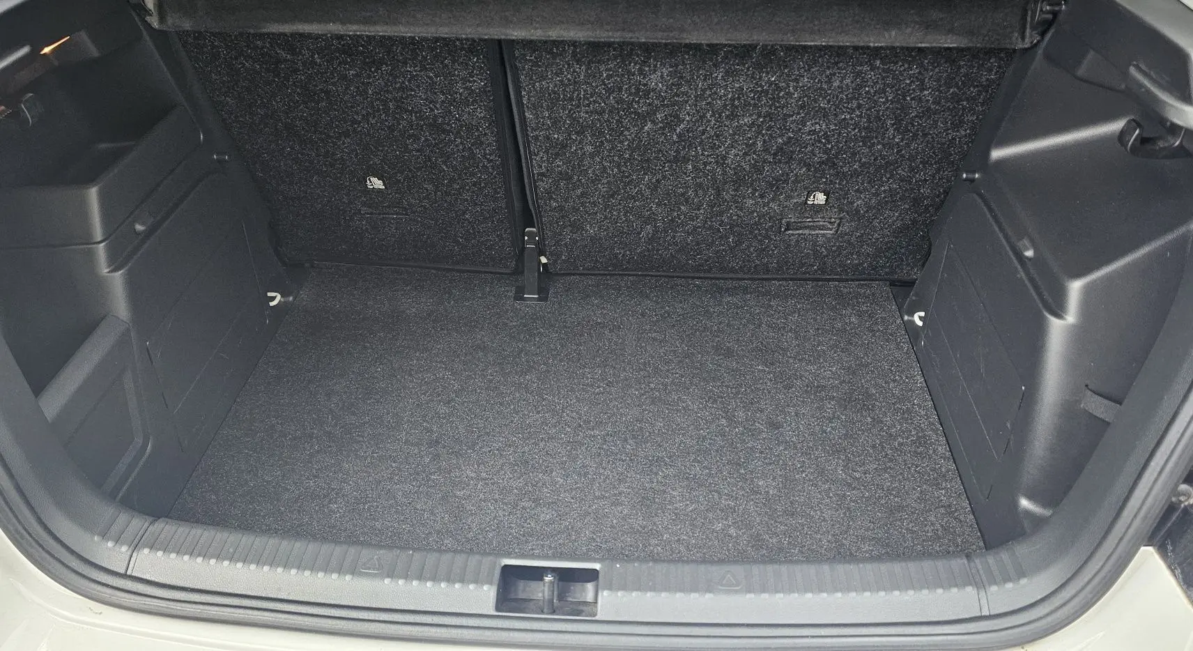 Coffre ouvert vu de face d'une Skoda Fabia 2020 blanc cristal, avec intérieur de coffre noir et tapis propre.