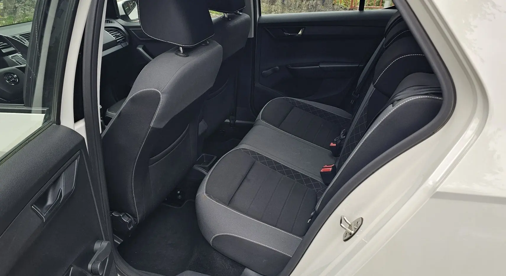 Vue côté gauche arrière de l'intérieur d'une Skoda Fabia 2020 blanc cristal, sièges noirs satin avec surpiqûres grises.