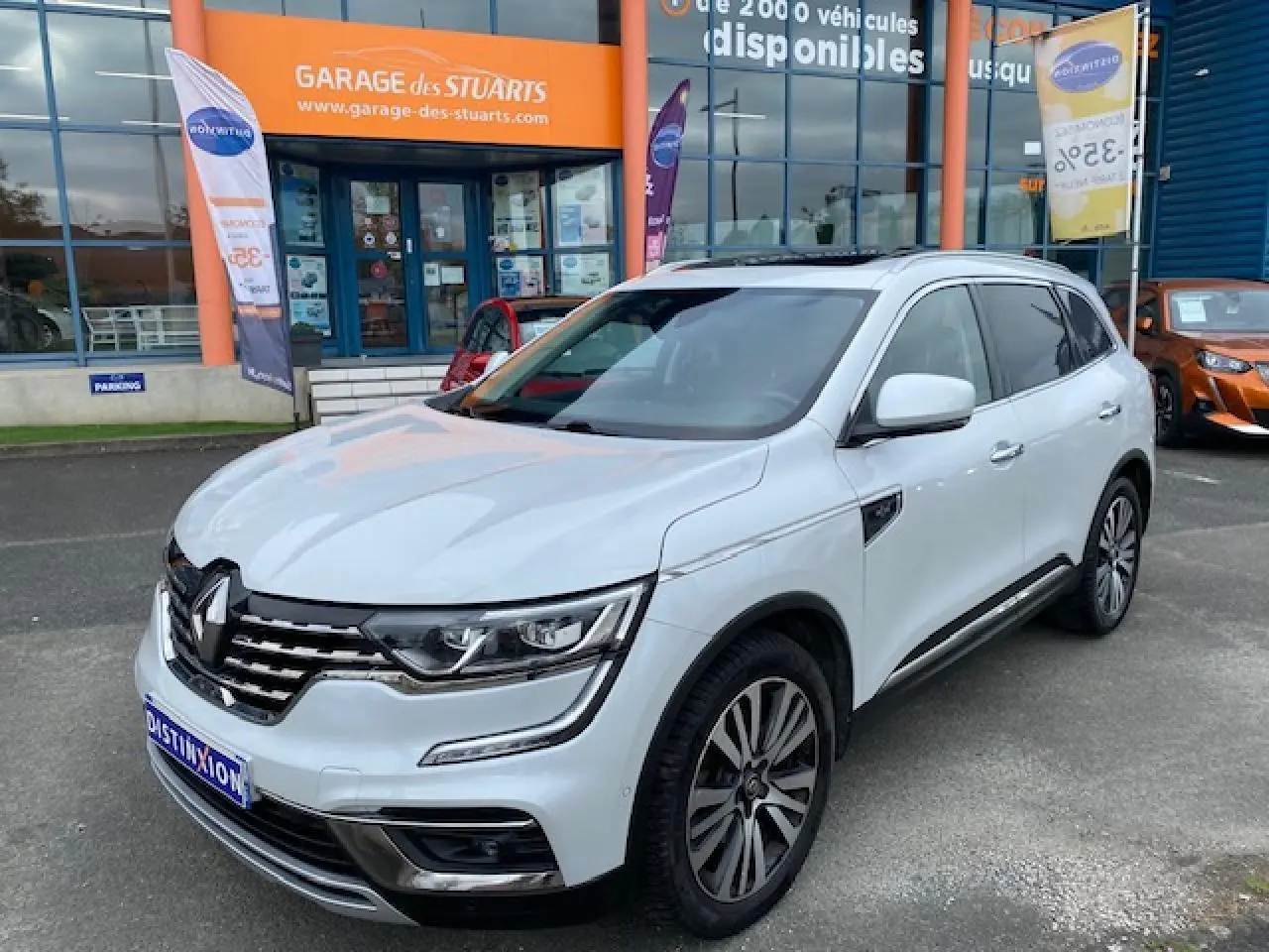 Renault Koleos blanc 2019 en 3/4 avant droit, avec calandre chromée et jantes alliage distinctives.