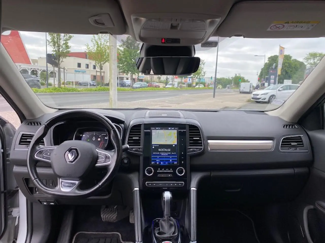 Vue intérieure frontale du tableau de bord noir du Renault Koleos blanc 2019 avec écran tactile et volant multifonction.