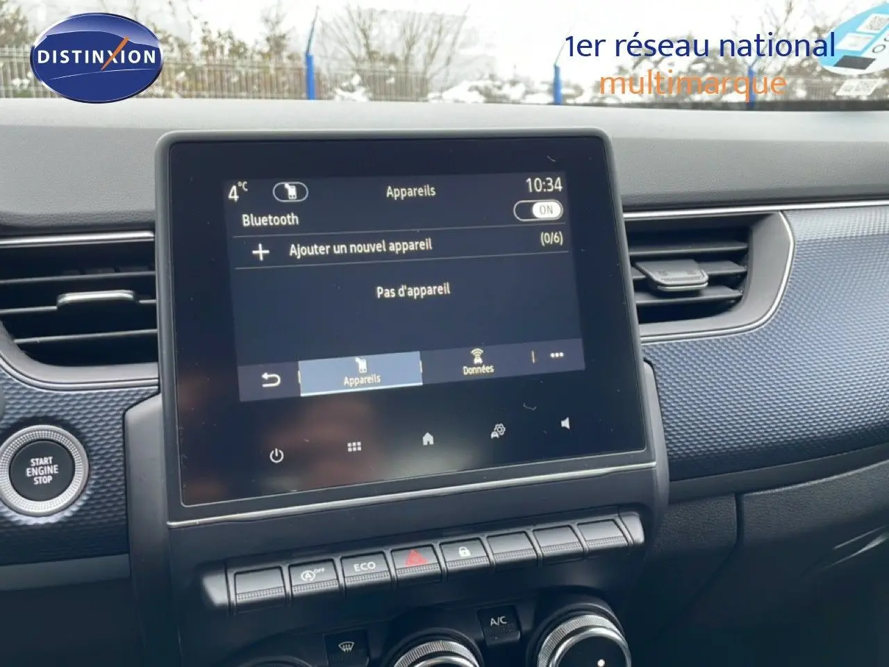 Vue rapprochée de l’écran tactile central et tableau de bord du Renault Arkana bleu Zanzibar, avec commandes climatisation et démarrage.