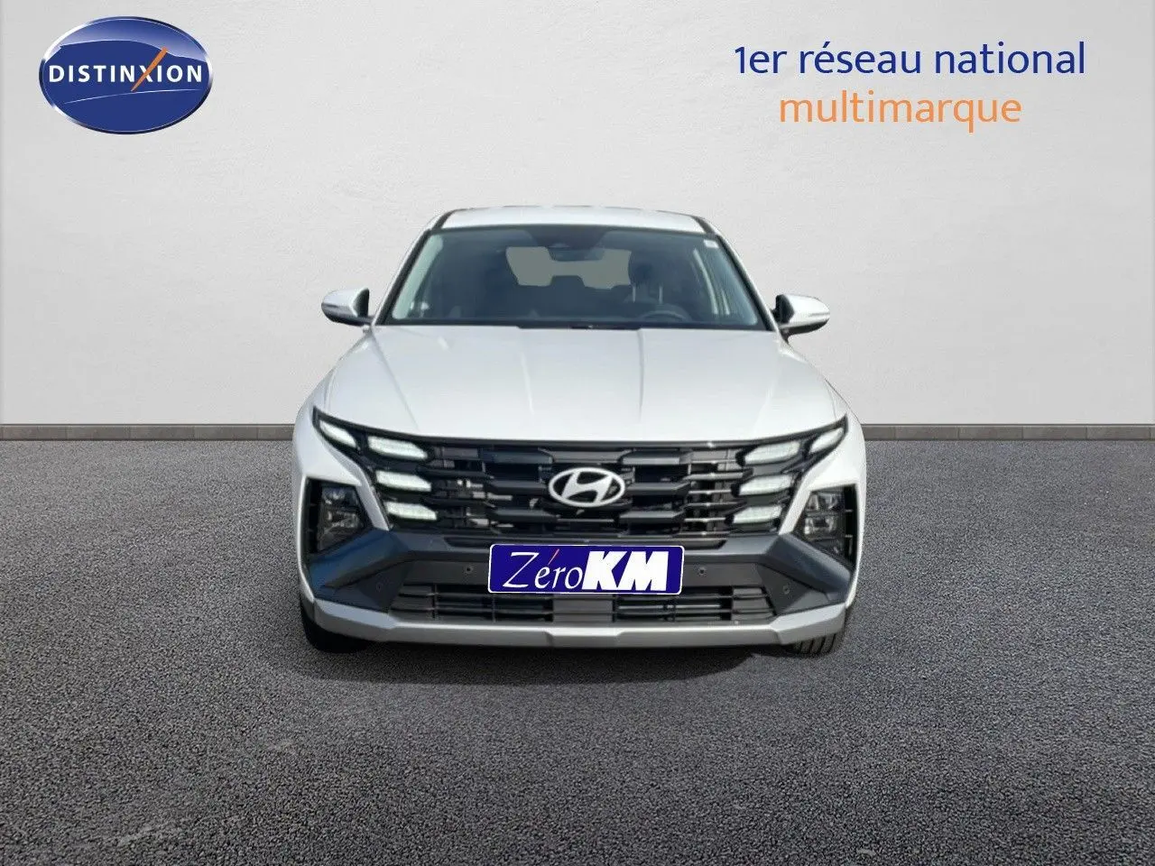 Vue frontale d'un Hyundai Tucson blanc Atlas 2026 avec calandre noire distinctive et feux LED intégrés.