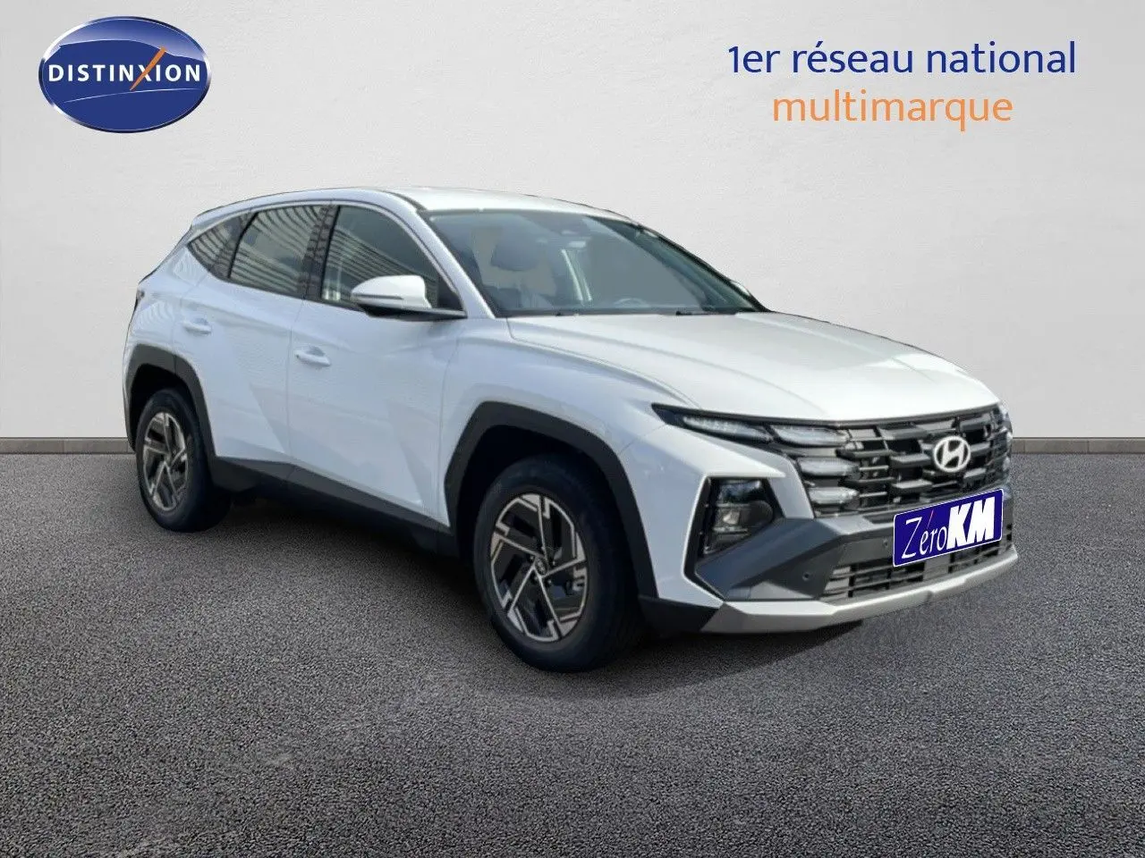 Vue 3/4 avant gauche d'un Hyundai Tucson blanc Atlas 2026 avec calandre noire et jantes bi-ton.