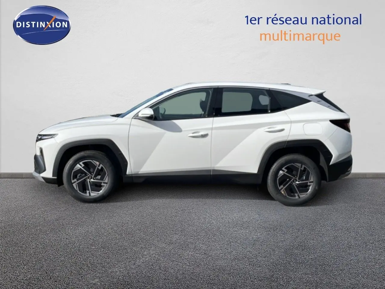Profil gauche du Hyundai Tucson blanc Atlas 2026, SUV hybride avec jantes bi-ton et lignes anguleuses marquées.