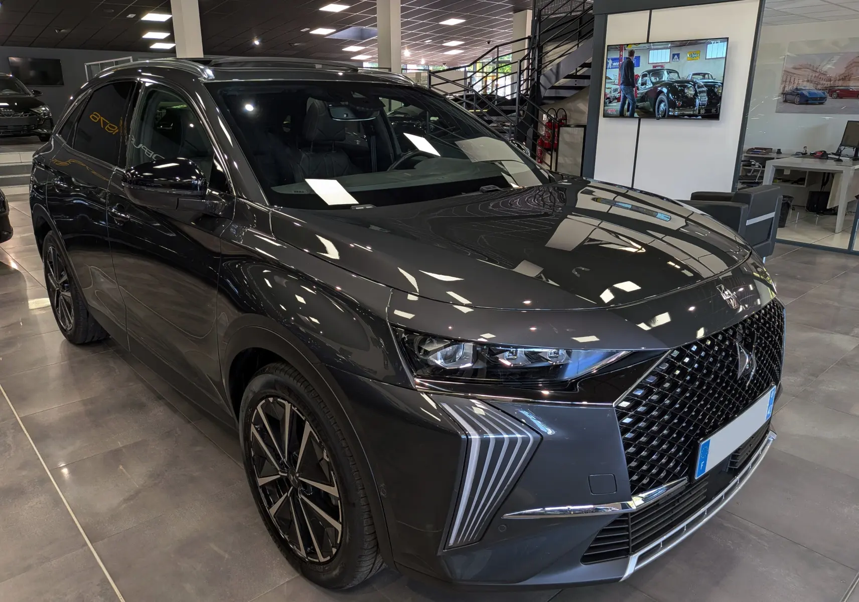 DS7 BlueHDi 130 gris 3/4 avant droit, avec calandre diamantée et feux LED verticaux distinctifs.