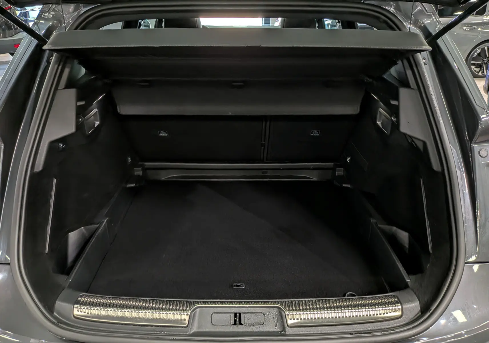 Coffre ouvert vu de l'arrière d'un DS7 2024 gris, montrant un espace de chargement propre et bien fini.