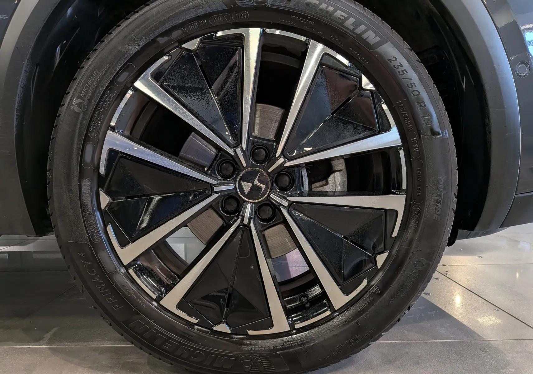 Gros plan sur la jante bicolore noire et argentée d’un DS7 gris, mettant en valeur le logo DS au centre.