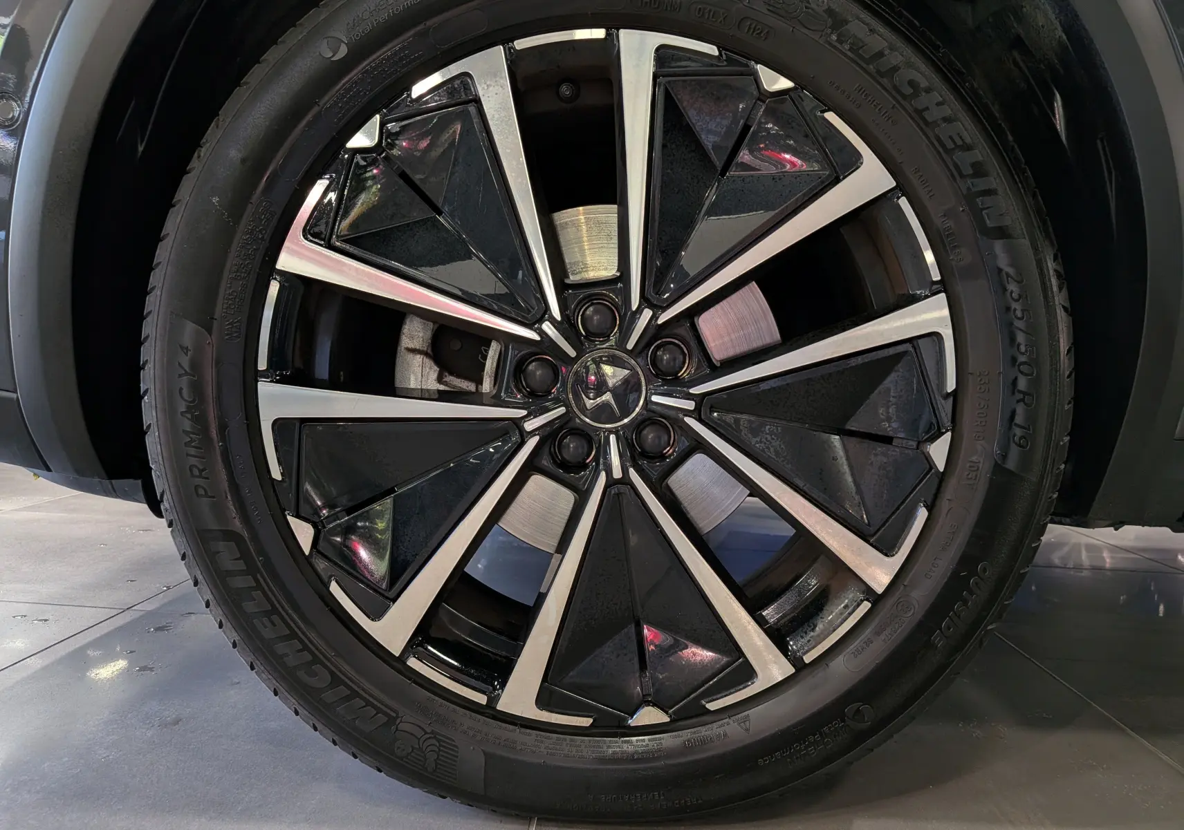 Gros plan sur la jante avant droite du DS7 gris 2024, mettant en valeur la roue alliage bicolore au design géométrique.