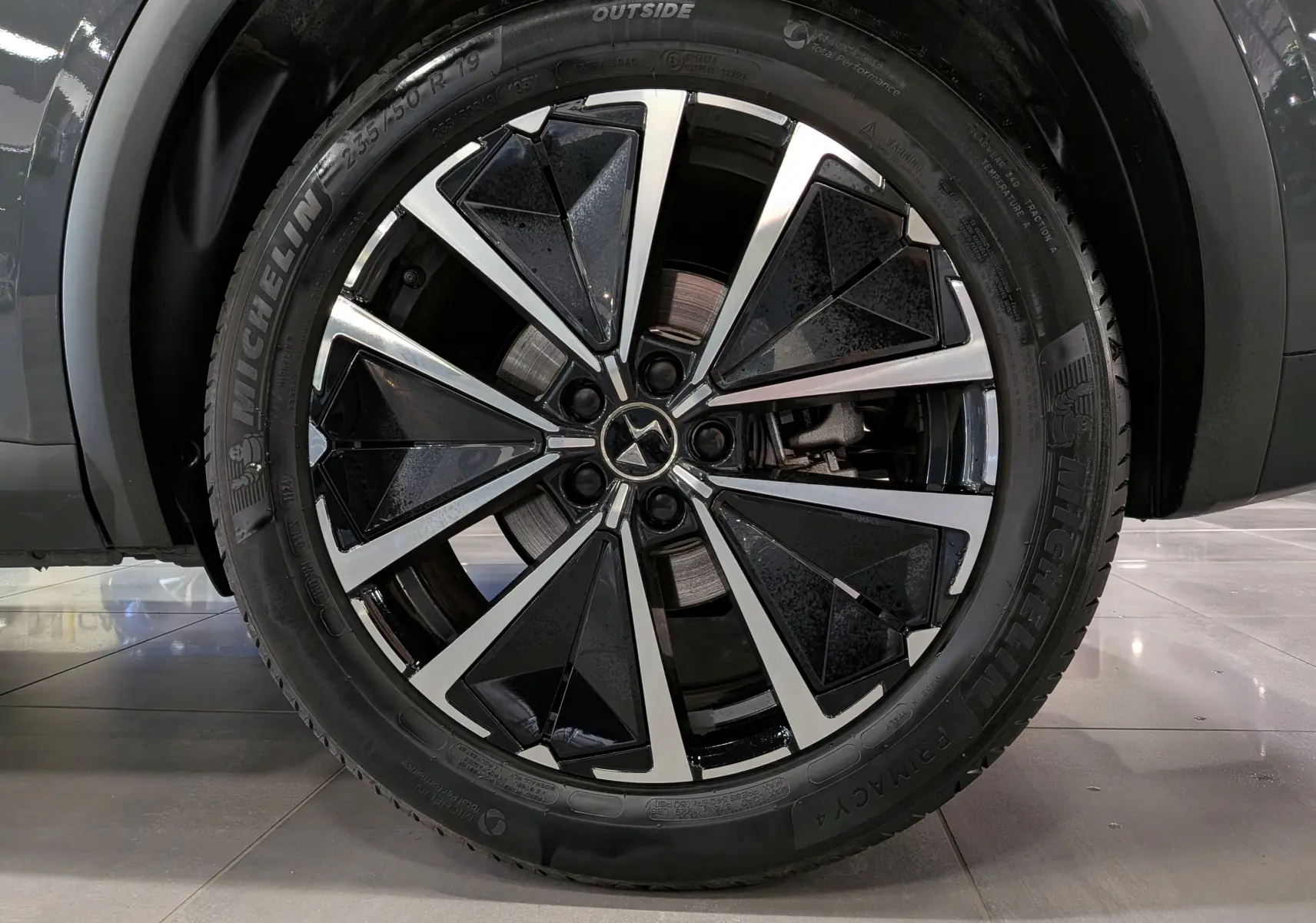 Gros plan sur la jante bi-ton noire et argent de 19 pouces du DS7 BlueHDi gris 2024, avec pneu Michelin visible.