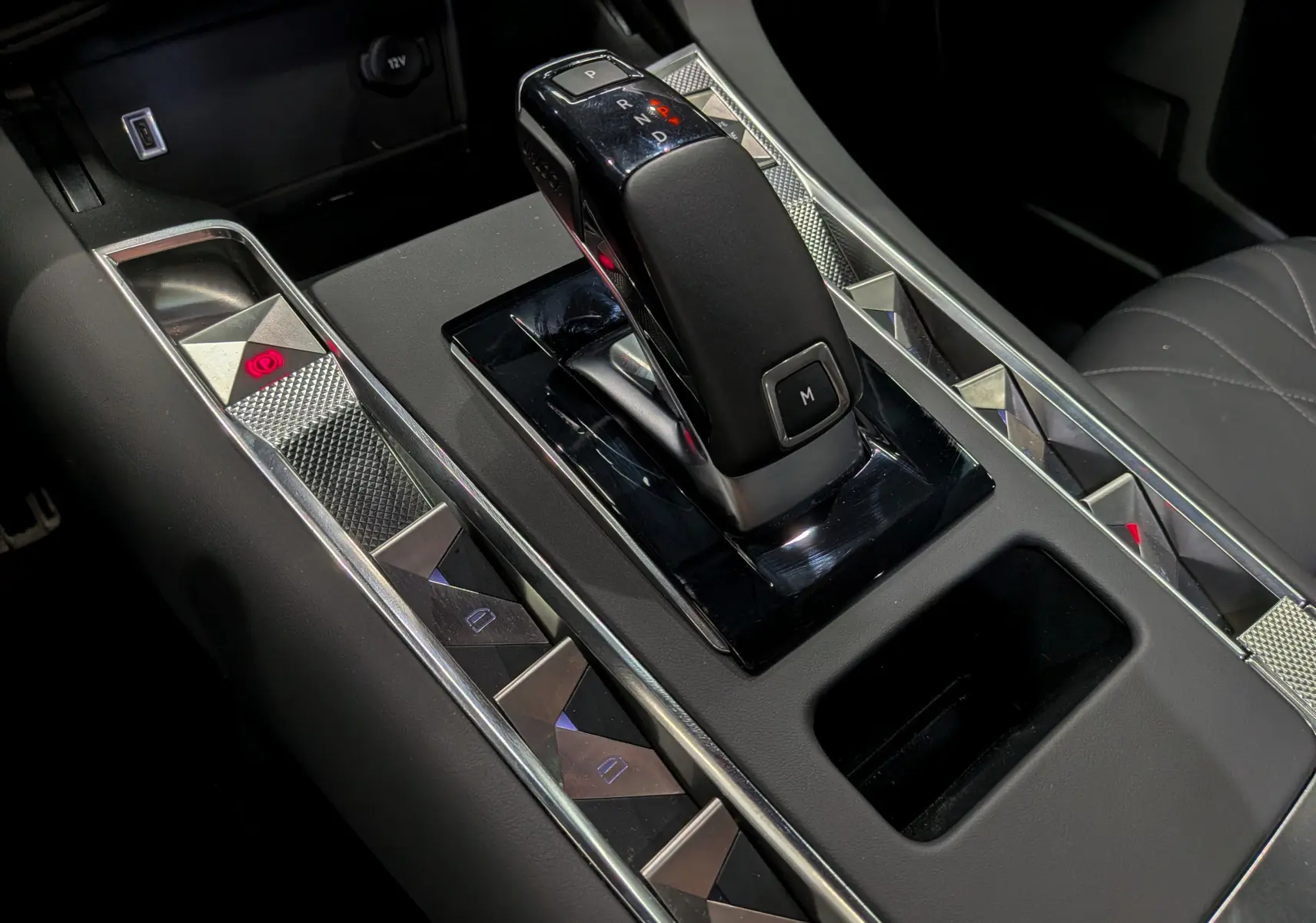Gros plan sur la console centrale du DS7 2024 gris, mettant en valeur le levier de vitesse automatique et les boutons à motifs géométriques chromés.