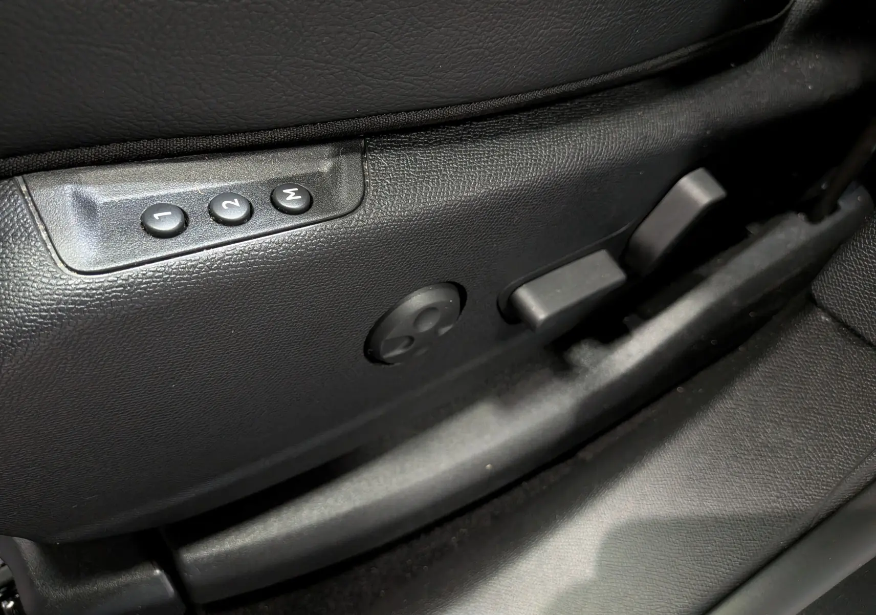 Détail des commandes de réglage électrique du siège avant en cuir noir dans un DS7 BlueHDi 2024.
