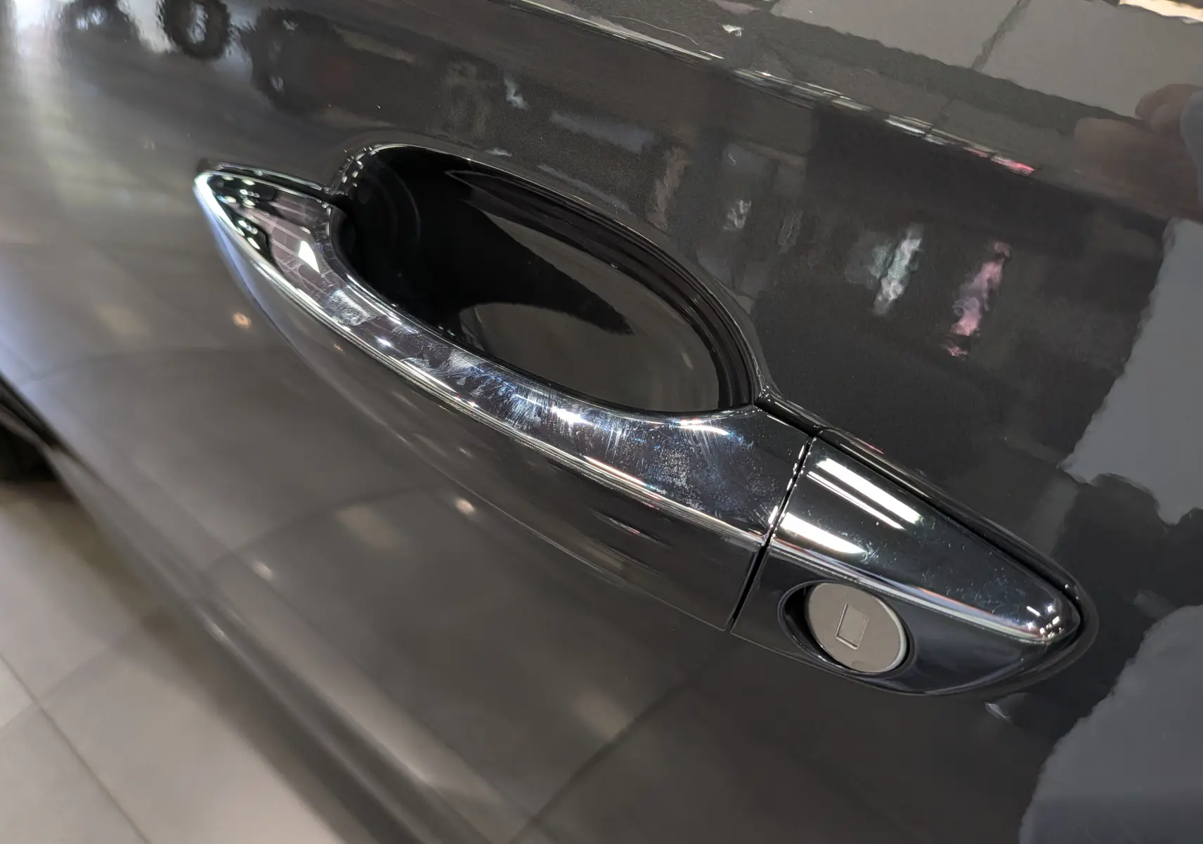 Poignée de porte chromée côté gauche sur DS7 BlueHDi gris 2024, reflet brillant sur la carrosserie métallique.