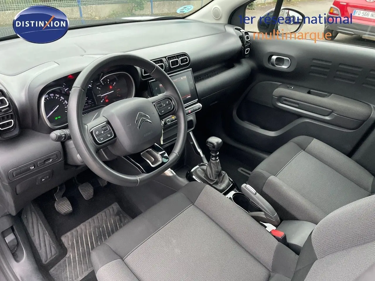 Vue intérieure côté conducteur du Citroën C3 Aircross gris platinium, montrant le tableau de bord et la boîte manuelle.