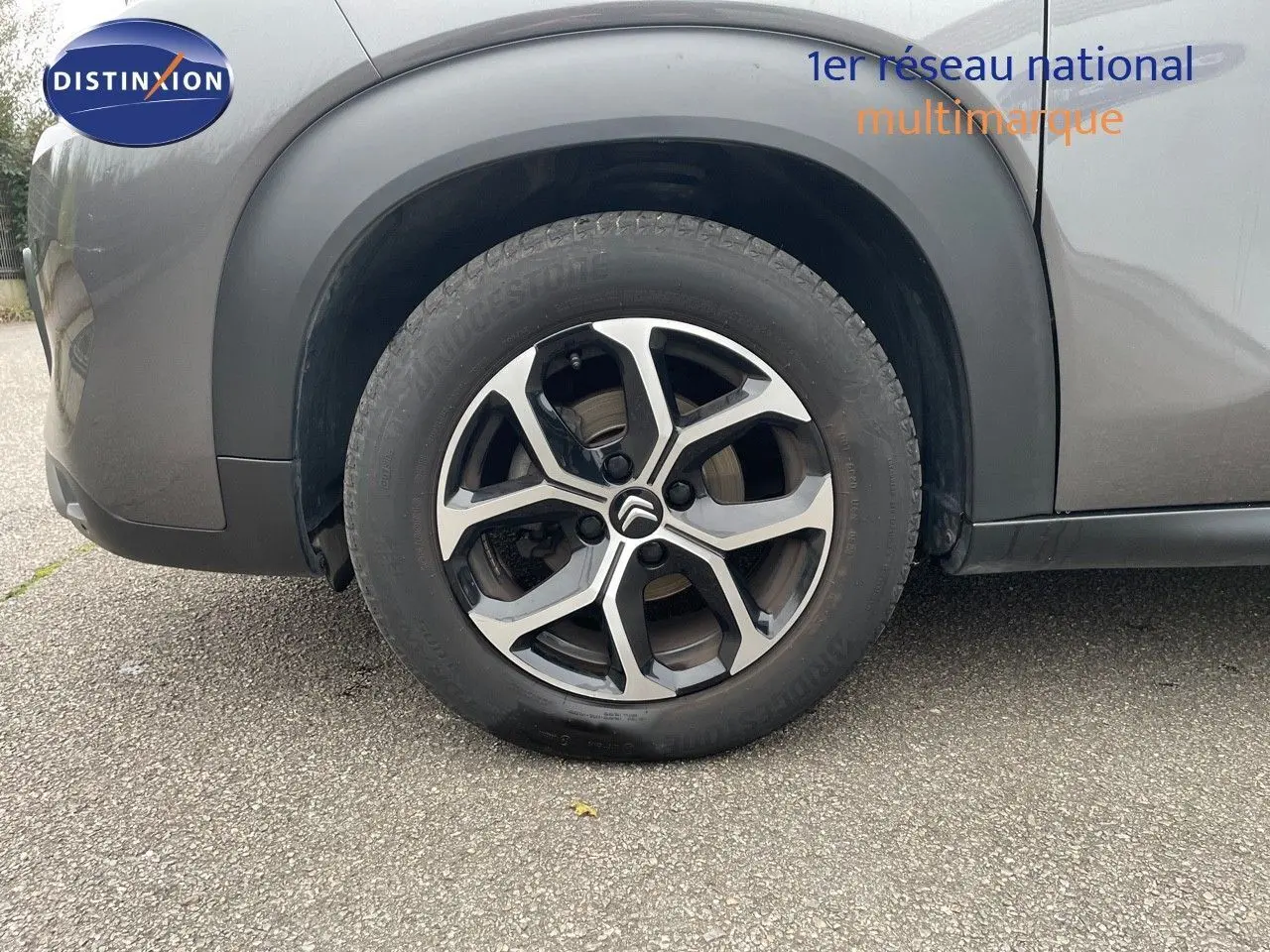 Gros plan sur la roue avant gauche d'un Citroën C3 Aircross gris platinium métal avec jante alliage bicolore.