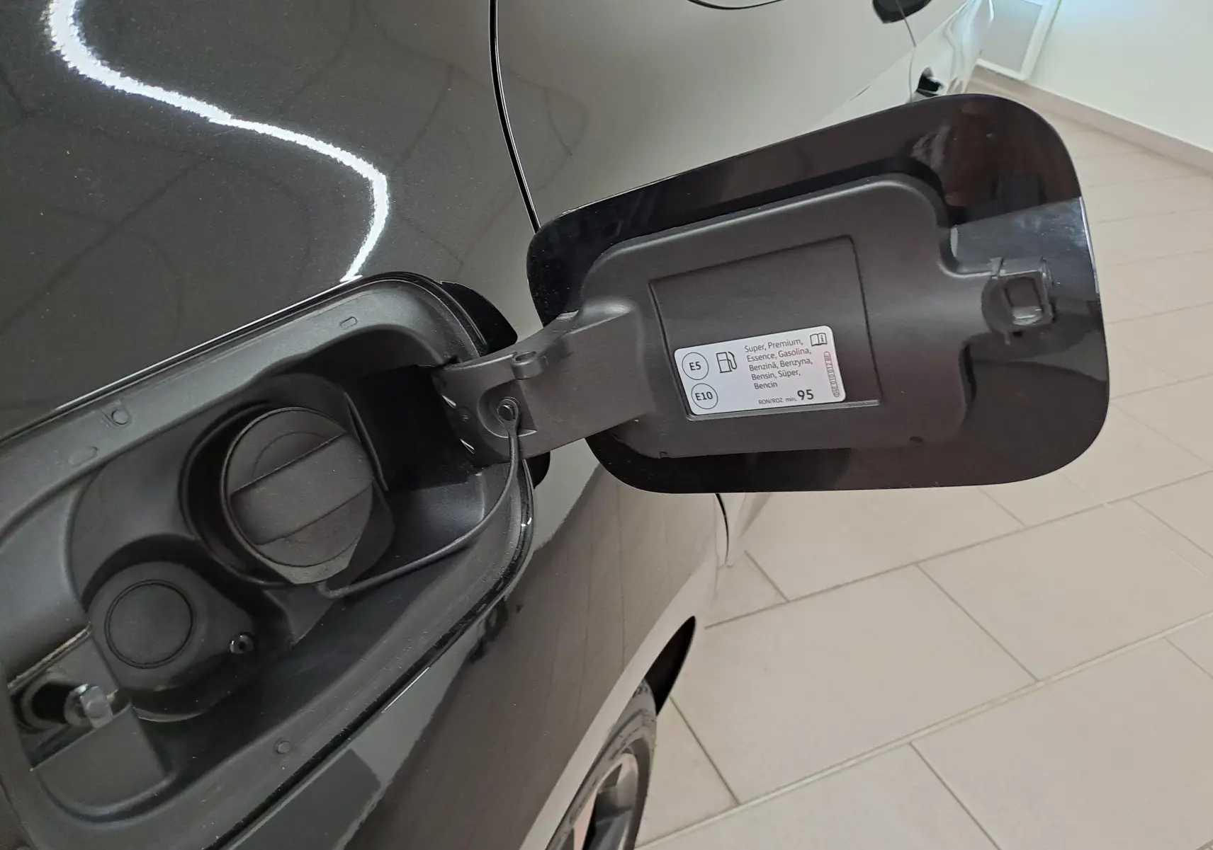 Gros plan sur la trappe à carburant côté gauche d'une CUPRA Leon Noir Minuit avec bouchon essence ouvert.