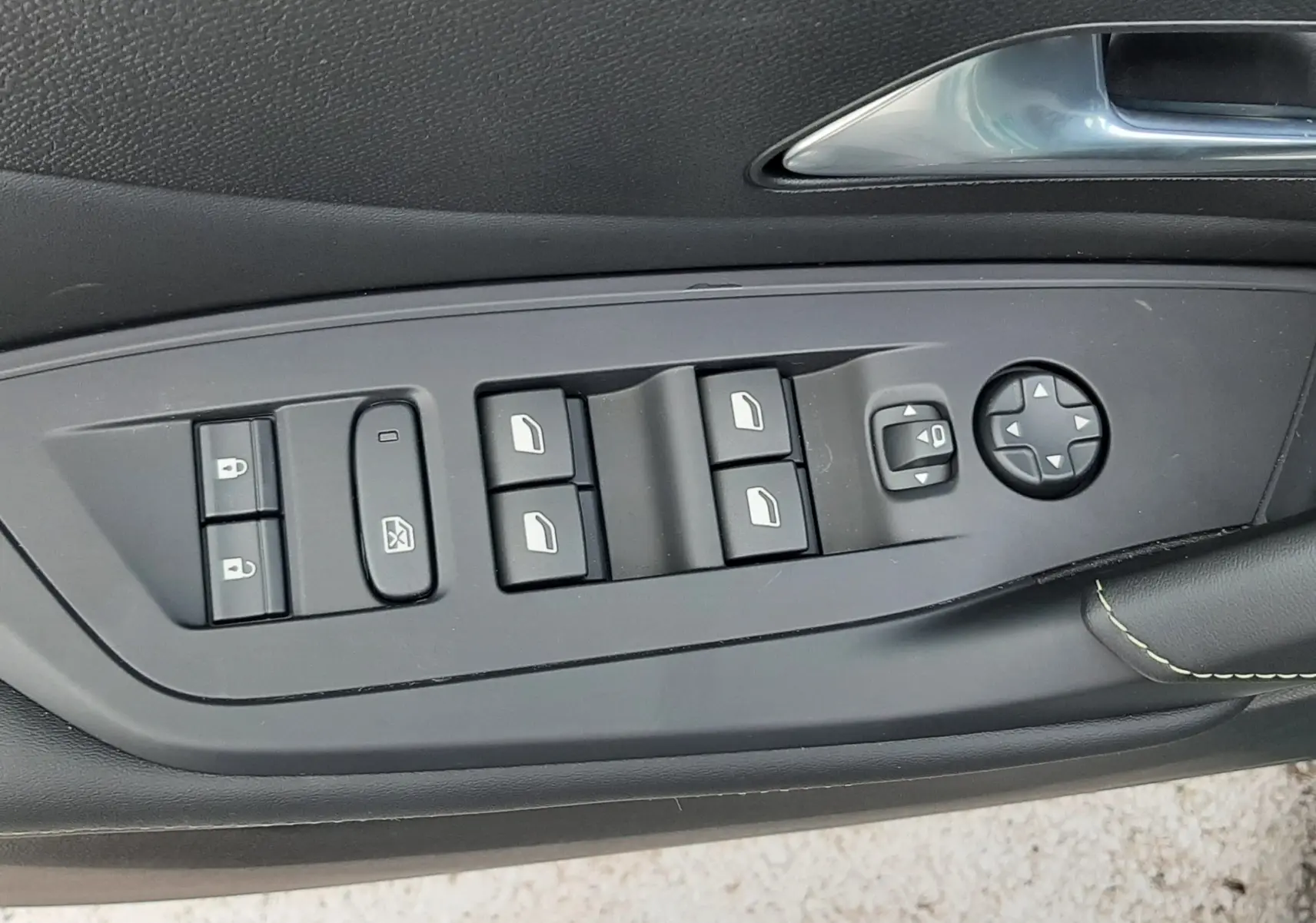 Détail des commandes de lève-vitres et rétroviseurs sur la porte intérieure noire d'une Peugeot 308 1.2 Hybrid 145ch GT.