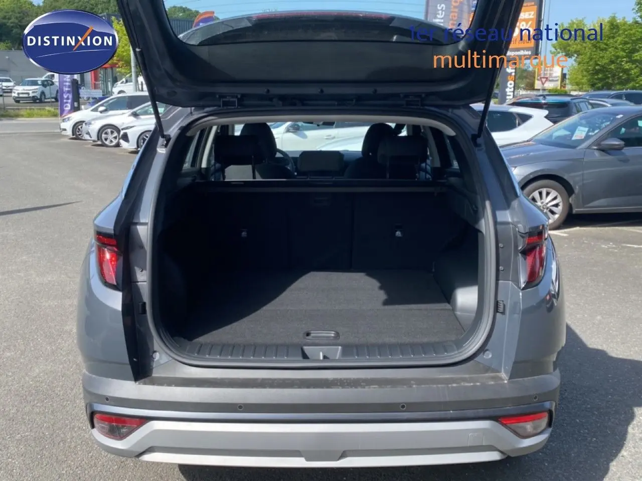Vue arrière du Hyundai Tucson gris Ecotronic Metal 2026 avec coffre ouvert et intérieur spacieux visible.