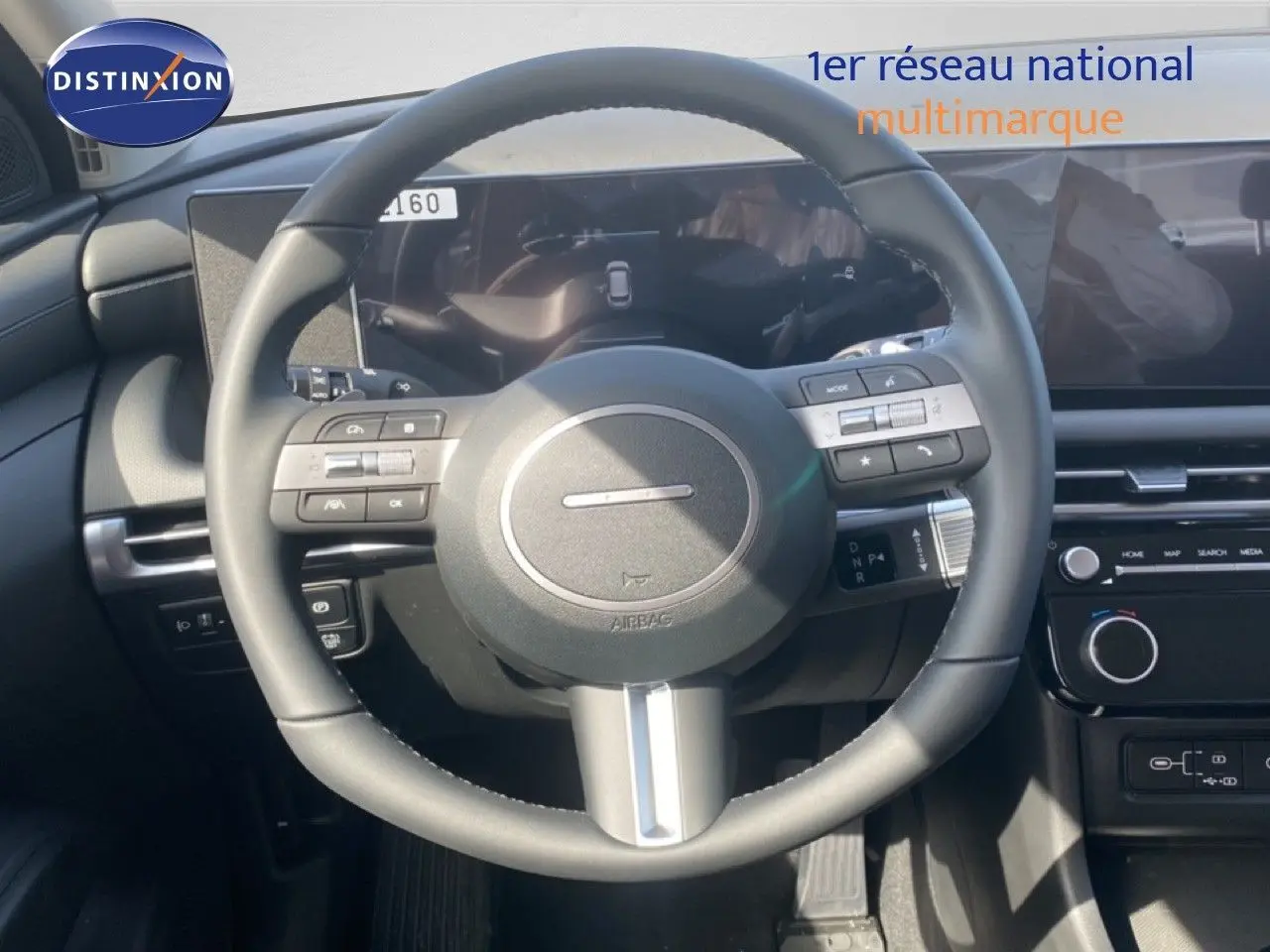 Vue intérieure centrée sur le volant cuir multifonction du Hyundai Tucson gris Ecotronic, avec tableau de bord digital.
