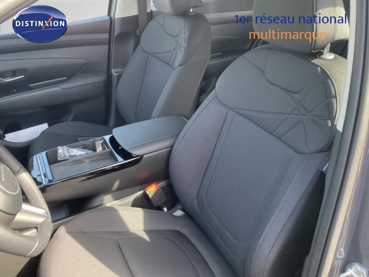 Vue intérieure côté gauche du Hyundai Tucson 2026, sièges tissu noir avec console centrale brillante.