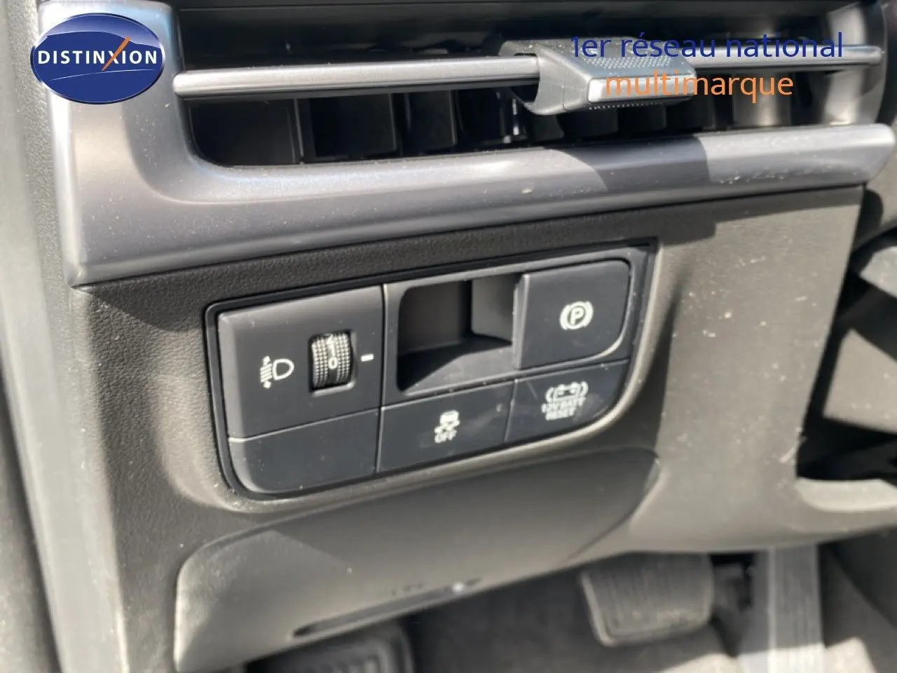 Gros plan sur les commandes de réglage des phares et frein de stationnement du Hyundai Tucson gris Ecotronic 2026.