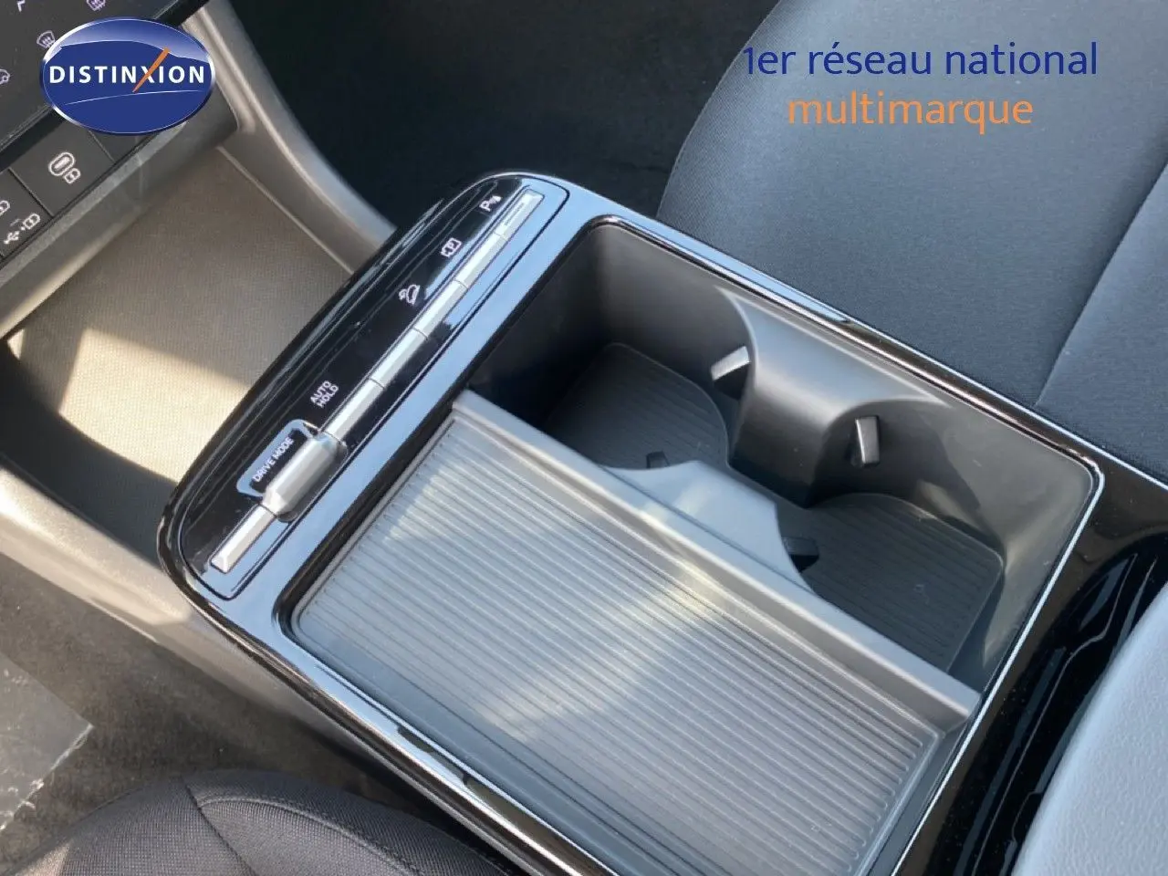 Vue rapprochée de la console centrale du Hyundai Tucson gris Ecotronic, avec porte-gobelets et commandes tactiles.