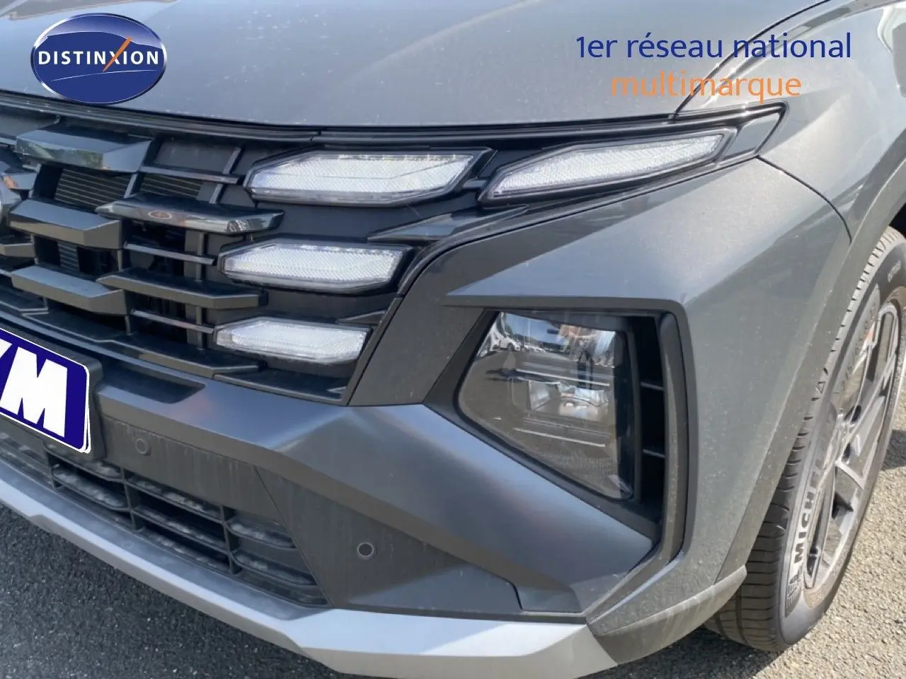 Gros plan sur l'avant droit du Hyundai Tucson gris Ecotronic Metal, mettant en valeur la calandre et les phares LED distinctifs.