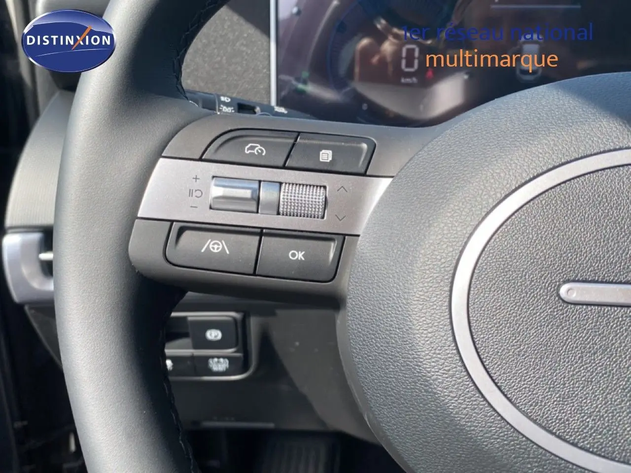 Gros plan sur le volant multifonction noir du Hyundai Tucson 2026, avec commandes intégrées et tableau de bord numérique flou.