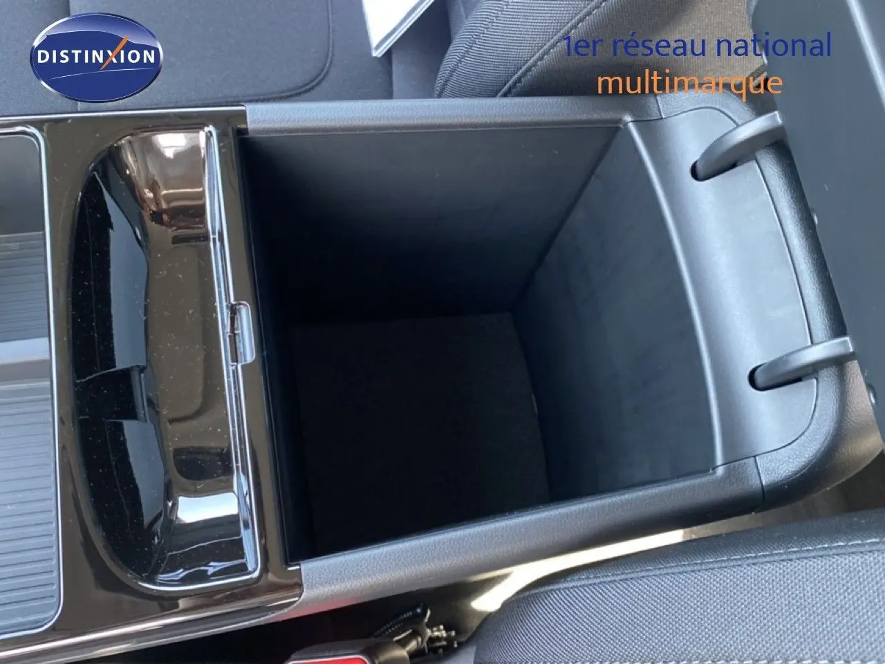 Vue en plongée sur le rangement central ouvert du Hyundai Tucson gris Ecotronic Metal, intérieur tissu noir visible.