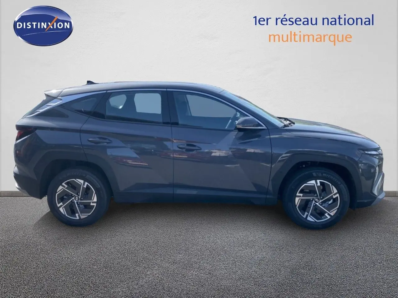 Vue de profil côté gauche d'un Hyundai Tucson gris Ecotronic Metal 2026 avec jantes alliage bicolores.