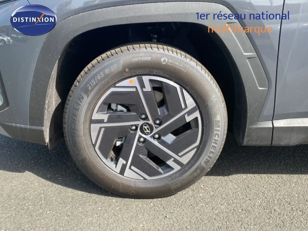 Gros plan sur la roue avant gauche du Hyundai Tucson gris Ecotronic Metal avec jante alliage noire et grise.