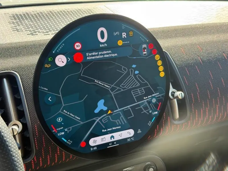 Vue rapprochée de l'écran circulaire multifonction du tableau de bord du MINI Countryman argenté, affichant la navigation.