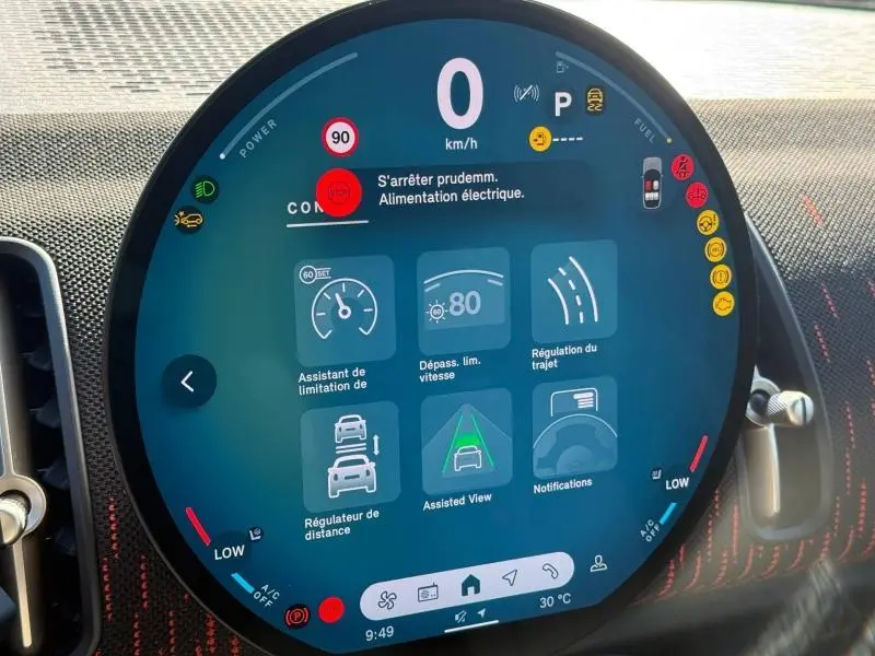 Gros plan sur l'écran circulaire digital du tableau de bord du MINI Countryman argenté, affichant les aides à la conduite.