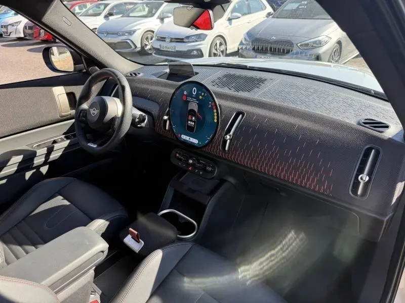 Vue intérieure côté conducteur du MINI Countryman 2025 avec tableau de bord texturé et écran circulaire digital.