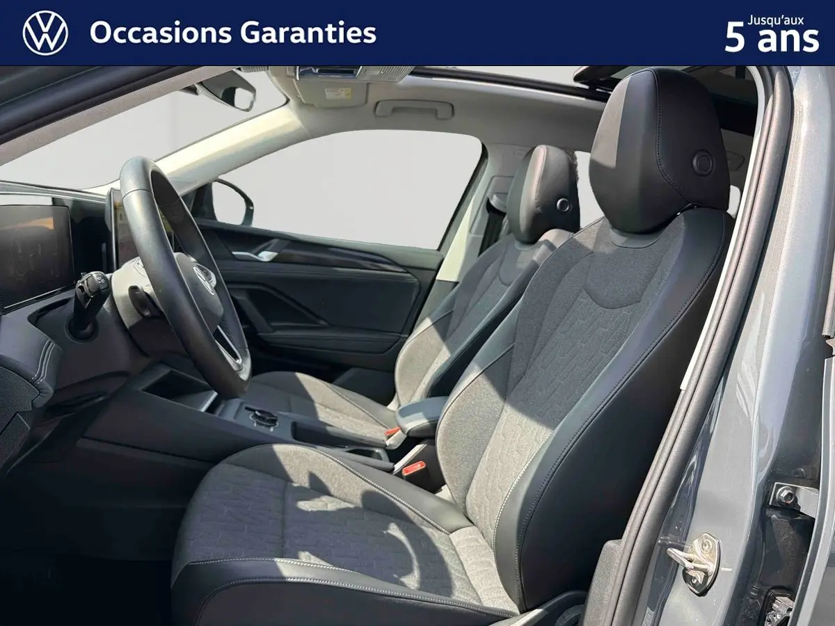 Intérieur avant du Volkswagen Tiguan gris 2025, vue côté droit sur les sièges tissu et cuir avec toit panoramique ouvert.