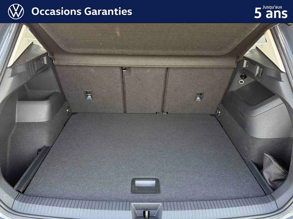 Coffre ouvert vu de l'arrière d'un Volkswagen Tiguan gris, montrant un espace de chargement propre et spacieux.