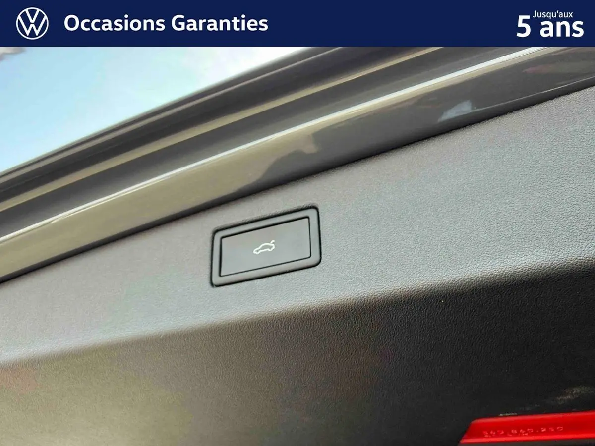 Bouton d'ouverture électrique du coffre sur la partie intérieure du hayon d'un Volkswagen Tiguan gris.