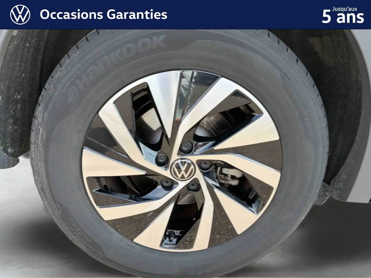 Gros plan sur la jante alliage Venezia noire et brillante du Volkswagen Tiguan gris, mettant en valeur le logo VW central.