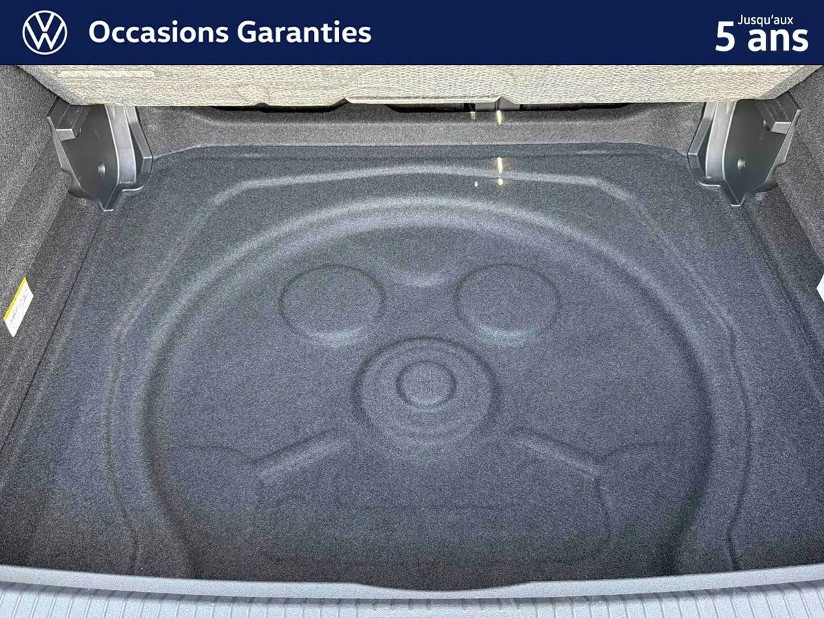 Coffre ouvert d’un Volkswagen Tiguan gris, vue plongeante sur le compartiment de rangement vide.