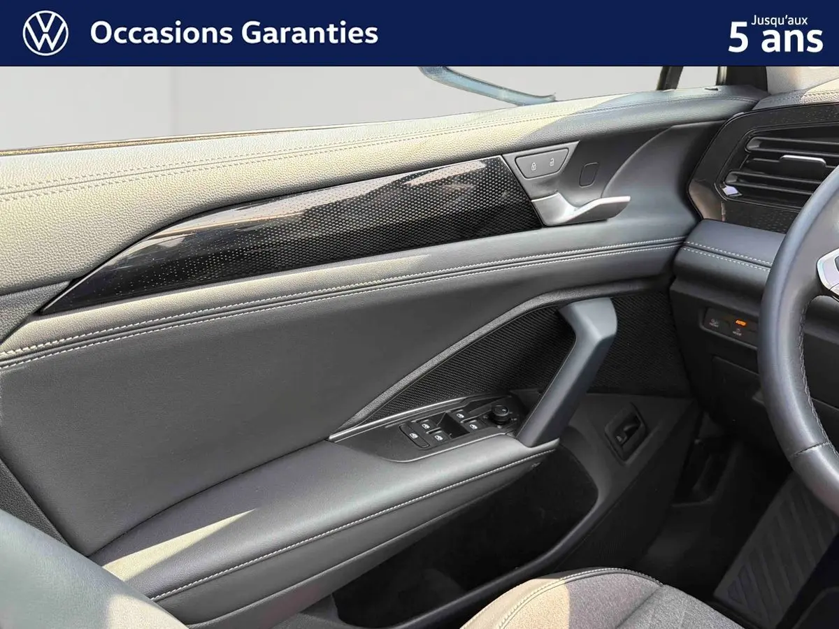 Détail de la porte avant gauche grise du Volkswagen Tiguan 2025 avec commandes électriques et insert décoratif noir brillant.