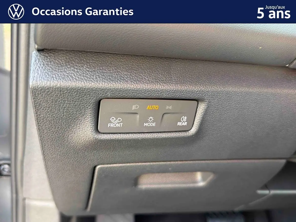 Détail du tableau de bord du Volkswagen Tiguan 2025 montrant les commandes d'éclairage automatiques en plastique noir texturé.