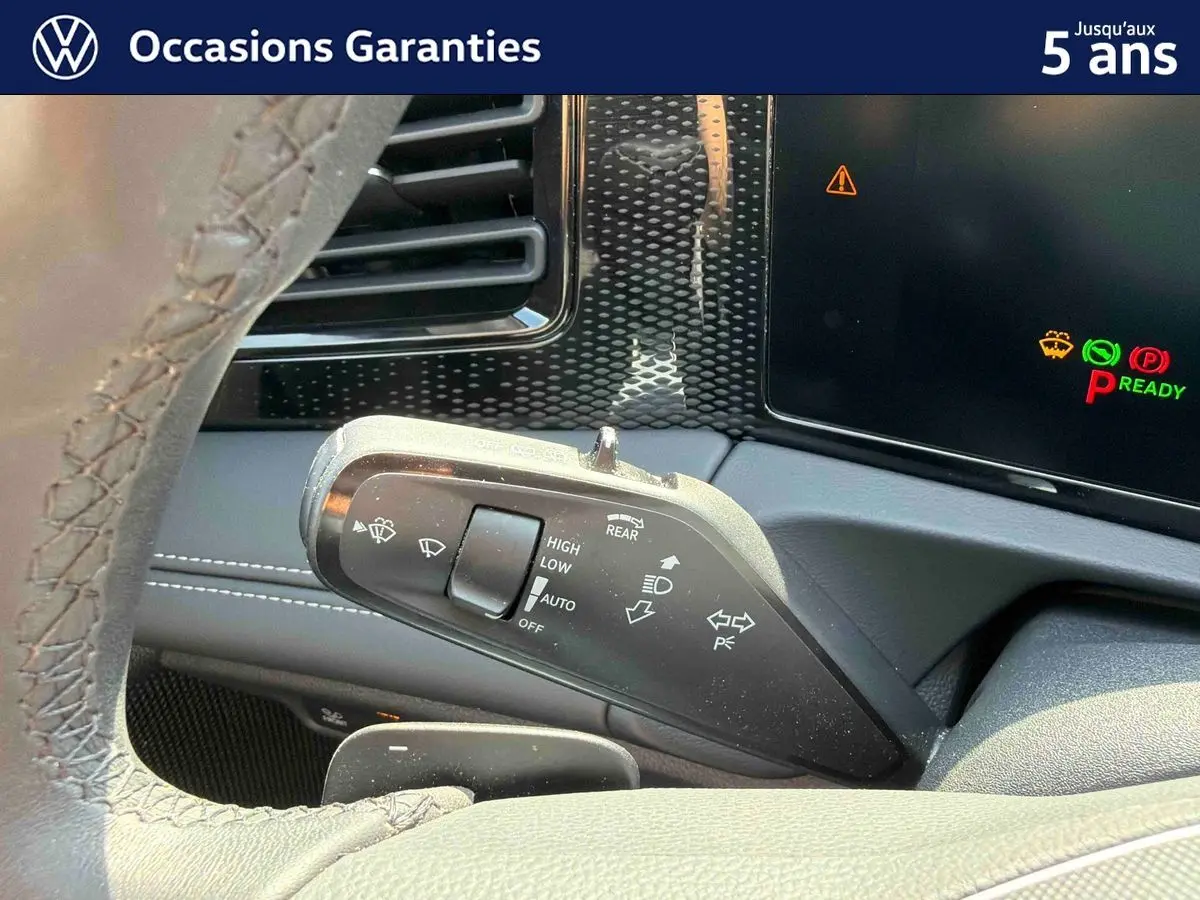 Gros plan sur la commande des essuie-glaces à gauche du volant dans l’habitacle d’un Volkswagen Tiguan gris.