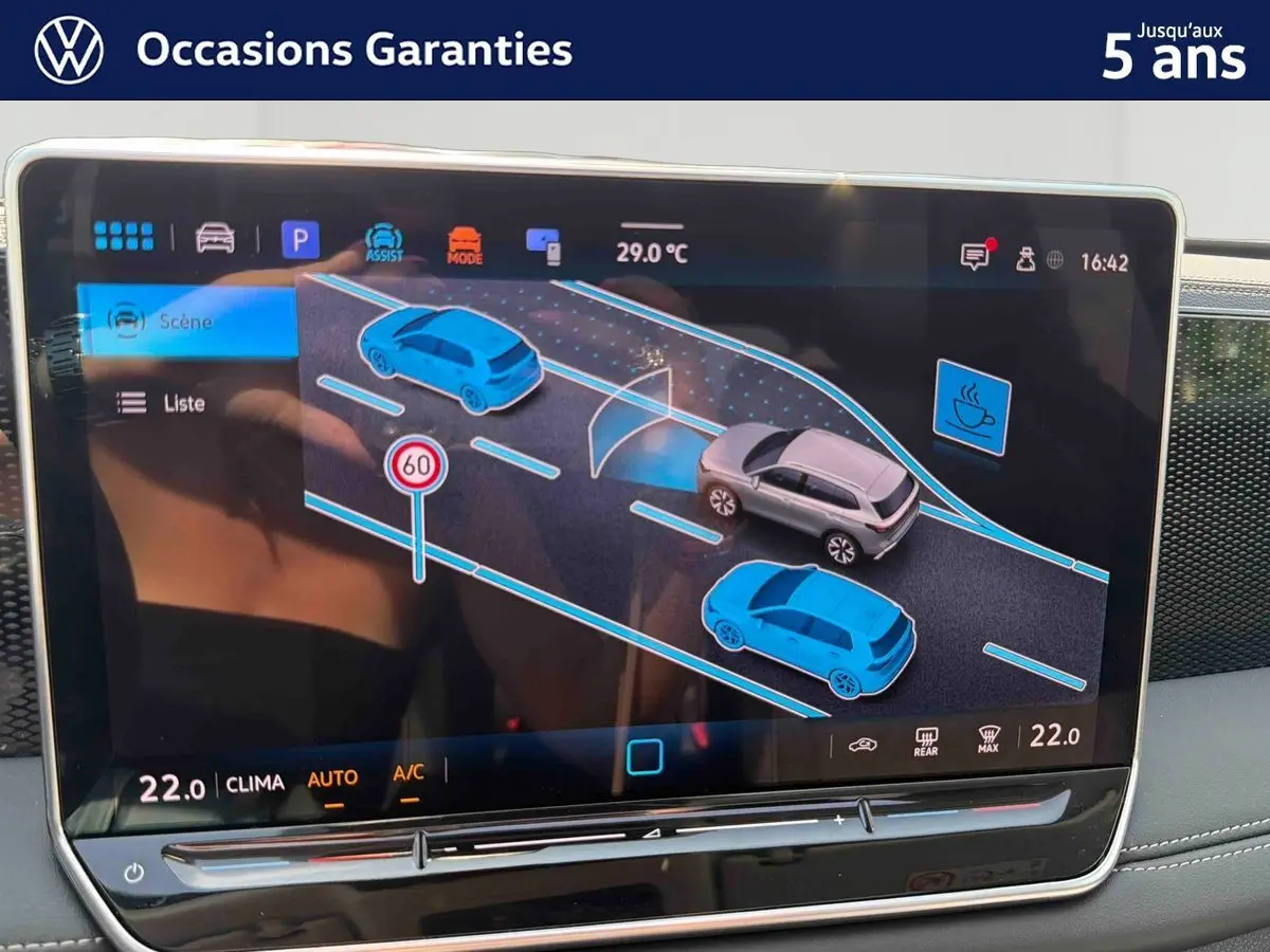 Écran tactile intérieur du Volkswagen Tiguan 2025 montrant l'assistance à la conduite avec véhicule gris en vue de profil.