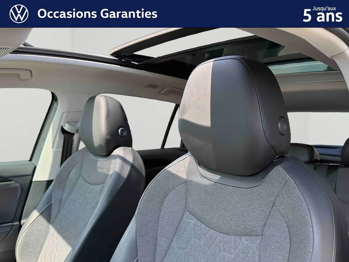 Gros plan sur les sièges avant gris et noirs du Volkswagen Tiguan 2025 avec toit panoramique ouvert.