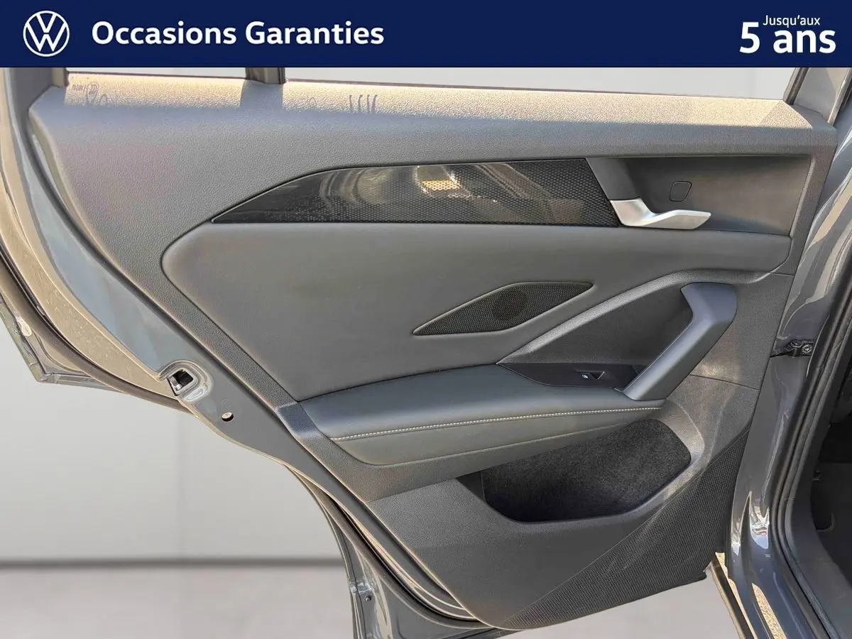 Vue rapprochée de la porte arrière gauche grise du Volkswagen Tiguan 2025 avec garniture noire et poignée argentée.