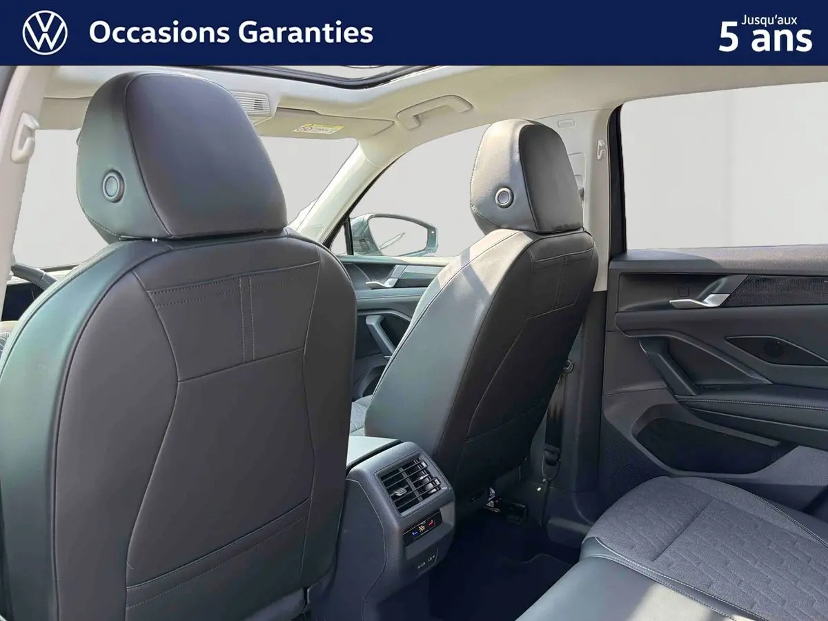 Vue arrière intérieure du Volkswagen Tiguan gris 2025, montrant les sièges avant en cuir et la console centrale avec aérateurs.